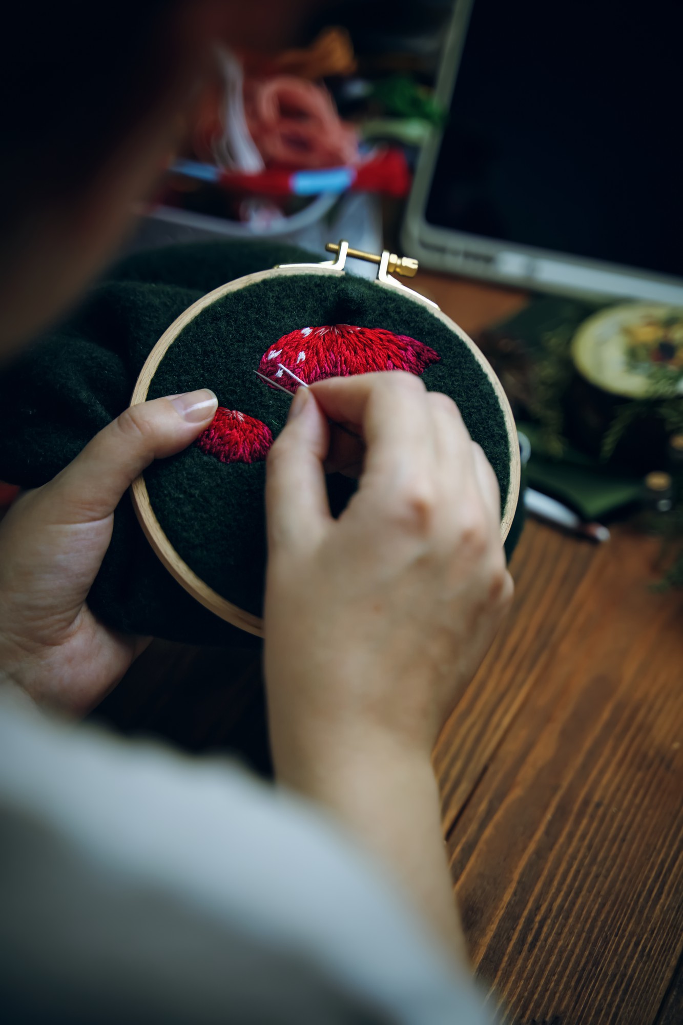 Hands finishing embroidered patch under lamp